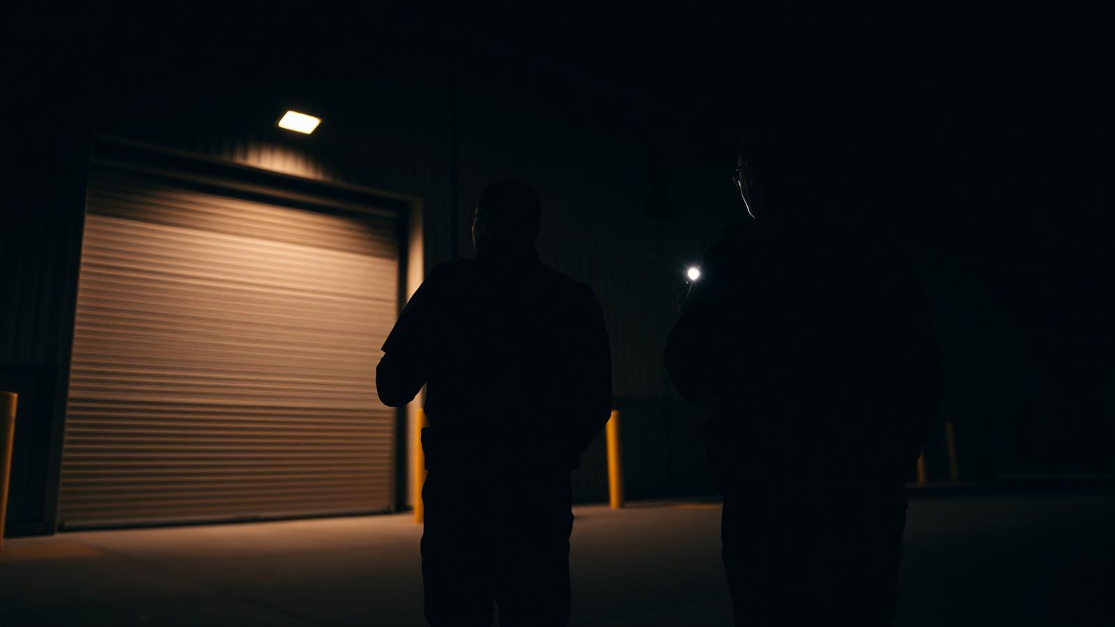 Two United Protective officers checking a warehouse roller door during a night walkthrough